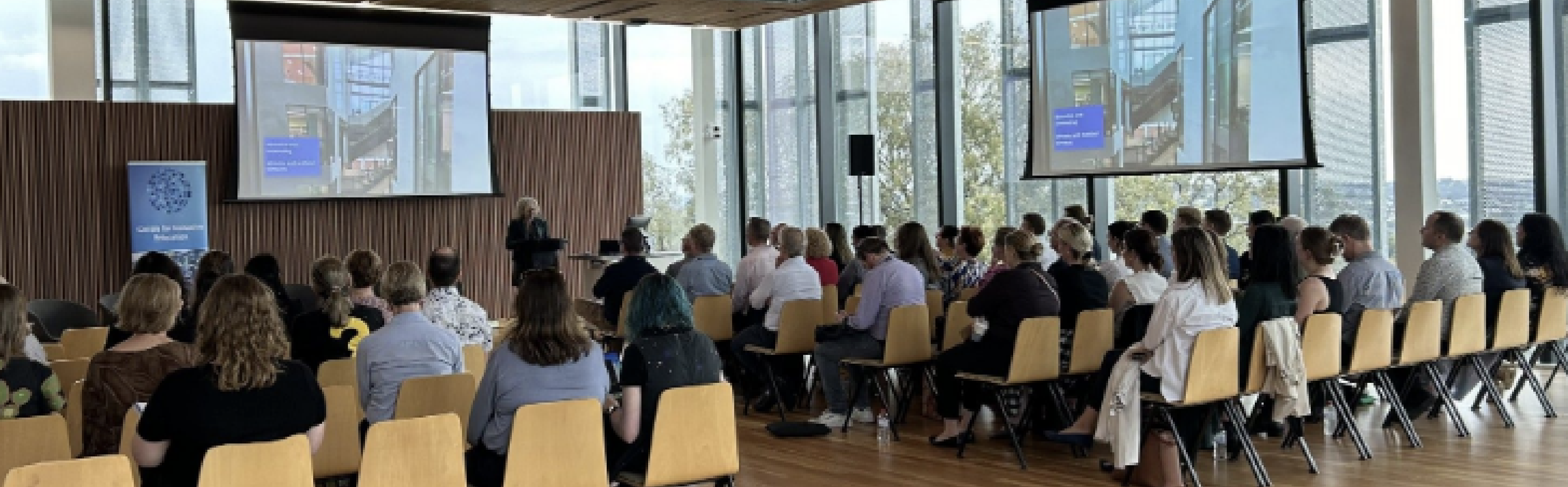 audience seated at the thriving in vertical schools forum as Professor Jill Willis presents.